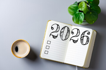 New year resolutions 2026 on desk. 2026 goals list with notebook, coffee cup, plant on table....