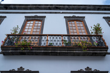 A balcony with two windows and a railing. The railing is made of iron and has a decorative design....