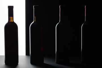 Red wine bottles silhouette over black background.