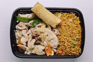 Top view of a Chinese takeout meal with Moo Goo Gai Pan served in a black plastic container...