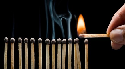 A hand lights a matchstick, igniting a row of matches