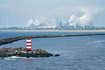 Harbour entrance with breakwave and lighthouse and oil refineries in background in Ilmuiden, Amsterdam, Netherlands