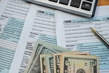 U.S. tax return forms with cash, pen, and calculator for annual income reporting 2025