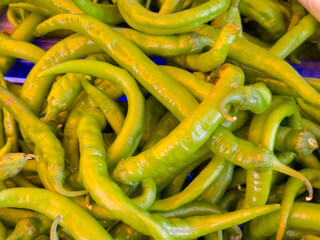 Fresh green chili peppers piled together in a market closeup