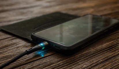 Illuminated Phone Charging on a Wooden Surface