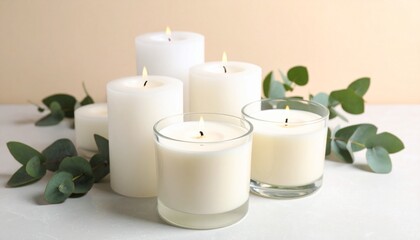 Nine lit white candles of varying heights arranged symmetrically with green leaves on neutral beige background, calm and natural setting