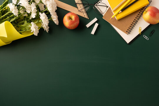 Greeting arrangement for Teacher's Day featuring flowers and school supplies on a green surface