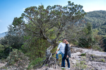 Naklejka premium Romantic Eco-Portrait: Couple Posing with Gnarled Tree at Dusk