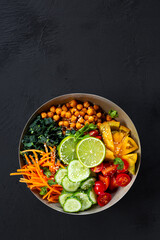 Buddha bowl - vegetarian bowl with chickpeas and fresh vegetables on the black background with copy...