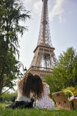 Girls sitting on grass during picnic with Eiffel Tower in background