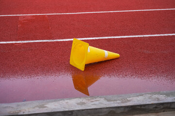 Yellow traffic cones lying on the running track for athletes at the stadium in the city.