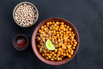 Vegetarian food. Roasted chickpeas with spices and lime in a bowl on black background top view