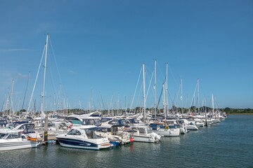 Fototapeta premium Lymington England - August 17 2025: boats in the marina at Lymington Hampshire with blue sky and clear reflections in the water