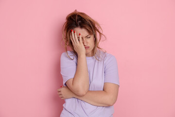 Woman suffering from hangover on pink background