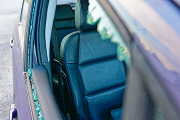 Shattered passenger window on purple car with black leather interior after burglary, theft, robbery