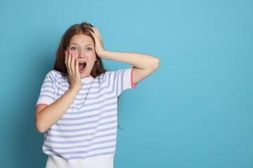 Teenage girl suffering from panic attack on light blue background. Space for text