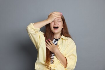 Teenage girl suffering from panic attack on grey background