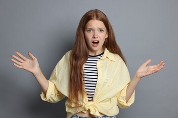 Teenage girl suffering from panic attack on grey background