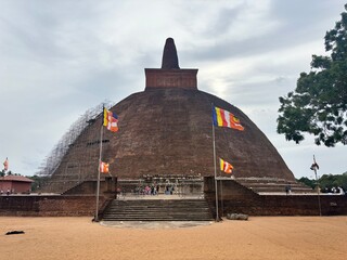 Majestic ancient Buddhist stupa 
Jetavanaramaya in Sri Lanka with colorful flags, showcasing...