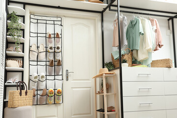 Organizer with different footwear, accessories and clothes indoors. Shoe storage