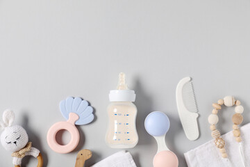 Bottle with milk and baby accessories on light grey background, flat lay. Space for text