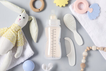 Bottle with milk and baby accessories on light grey background, flat lay