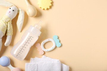 Bottle with milk and baby accessories on beige background, flat lay. Space for text