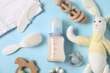 Bottle with milk and baby accessories on light blue background, flat lay