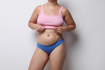 Liposuction. Woman in underwear on light grey background, closeup