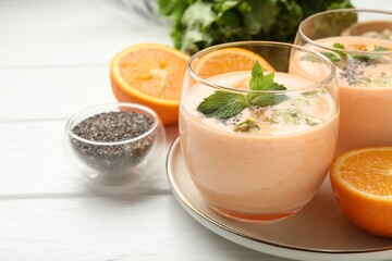 Superfood. Tasty smoothie with chia seeds, mint, pistachio and oranges on white wooden table, closeup