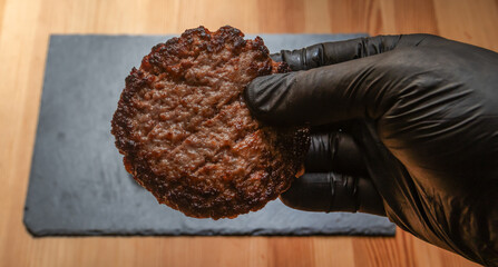 A person in black latex gloves holds a delicious hamburger with fresh ingredients. Perfect for food, restaurant, and menu concepts.