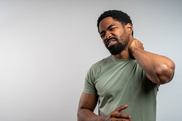 Young African man suffering from neck pain isolated on white background with copy space for medical...