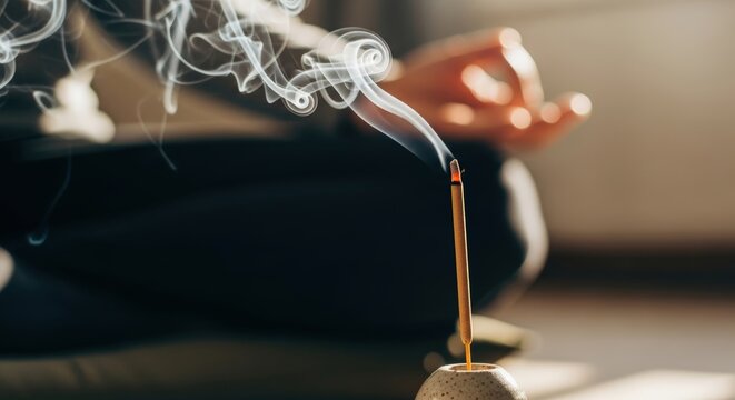 Person meditating with burning incense stick meditation