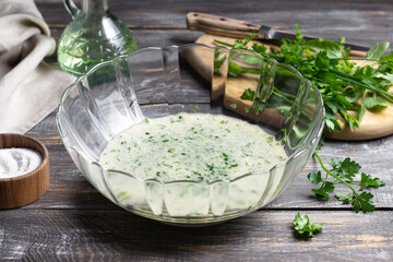 Fresh herb and egg mixture in glass bowl on rustic table, ingredient preparation for omelette or savory dish