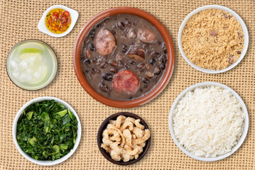 Traditional brazilian feijoada with kale, manioc flour, rice, pepper, cracklings and caipirinha