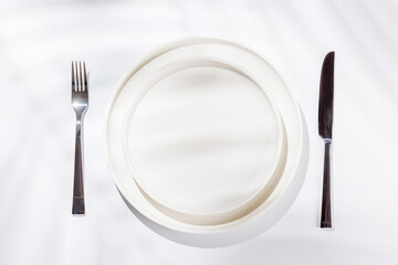 Empty plate on a white background with leaf shadows, perfect food mockup