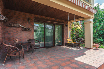 Covered porch with seating area and swing in a suburban home near a garden