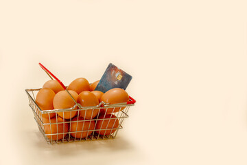 eggs in a shopping basket with a bank card on a beige background with copy space