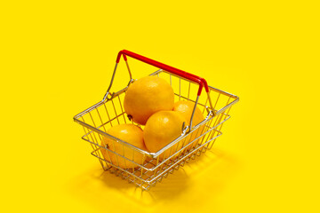 shopping basket with lemons on yellow background