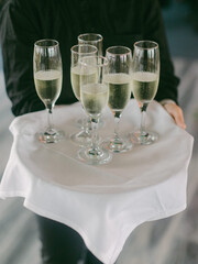 Waiter serves sparkling drinks on tray at a festive event in a sophisticated setting