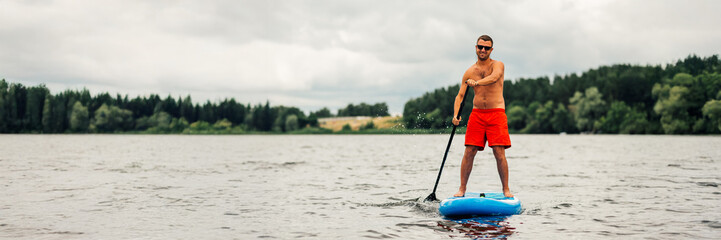 Man Paddleboarding on Lake Wide Banner with Copy Space
