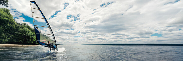 Windsurfer on Water Under Cloudy Sky Banner