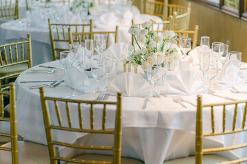 Elegant dining setup with floral centerpiece in a banquet hall for a special event