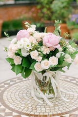 Lovely floral arrangement with peonies and roses on a mosaic table in a garden setting