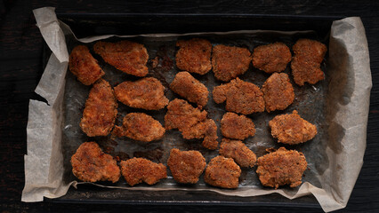 Close-up view of crispy fried chicken nuggets coated in golden batter. High-calorie fast food meal rich in fat and oil. Unhealthy snack or comfort food often associated with junk food