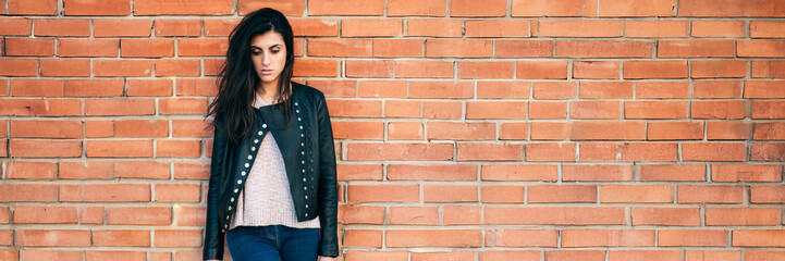 Pensive Woman Against Brick Wall Wide Banner with Copy Space