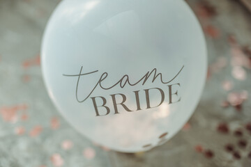 A decorative balloon floats gently with the words team bride, surrounded by shimmering confetti and...