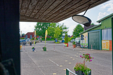 Round mirror on wooden roof with metal support near parking