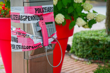 Mounted phone on metal pole with police tape and pink cover