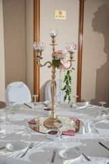 A beautifully arranged dining table features an ornate candelabrum surrounded by delicate flowers,...